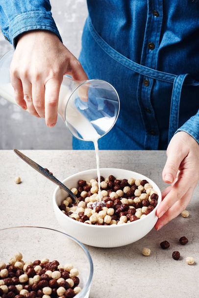 Les mains féminines versent le lait dans un bol de céréales pour petit déjeuner. - Photo, image
