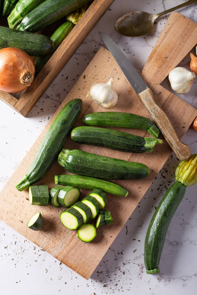 Fresh green zucchini on wooden board with knife. Top view. - Photo, image