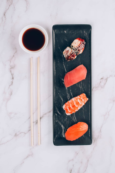 Conjunto de sushi nigiri japonés tradicional, salsa de soja y palillos sobre fondo de mesa de mármol blanco con atún crudo, salmón, camarones y anguila. Comida asiática entrega y sushi bar menú concepto - Foto, Imagen