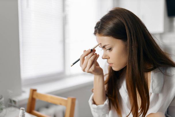 femme avec crayon eyeliner fond de teint maquillage à la maison - Photo, image