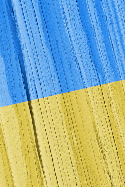 Flag of Ukraine on dry wooden surface, cracked with age. Vertical background or mobile phone wallpaper with Ukrainian national symbol. Light faded paint on old wood. Hard sunlight with shadows - Foto, imagen