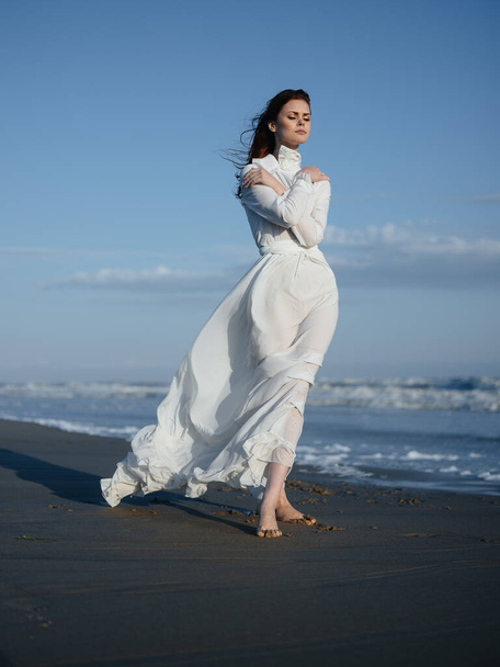 Жінка в білій сукні ходить на мокрому піску на березі океану
 - Фото, зображення