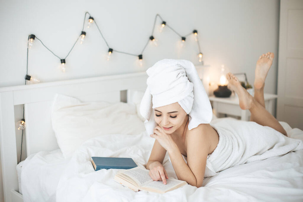 Young happy woman reading paper book in bed. - Fotó, kép