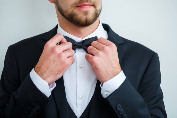 Stylish man groom puts a bow tie around his neck - Фото, изображение