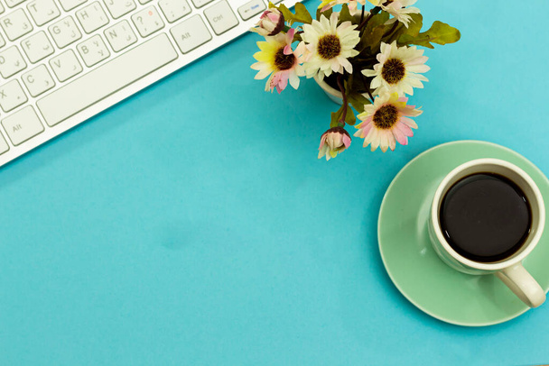 Современная алюминиевая клавиатура, чашка кофе и ваза с цветами. - Фото, изображение