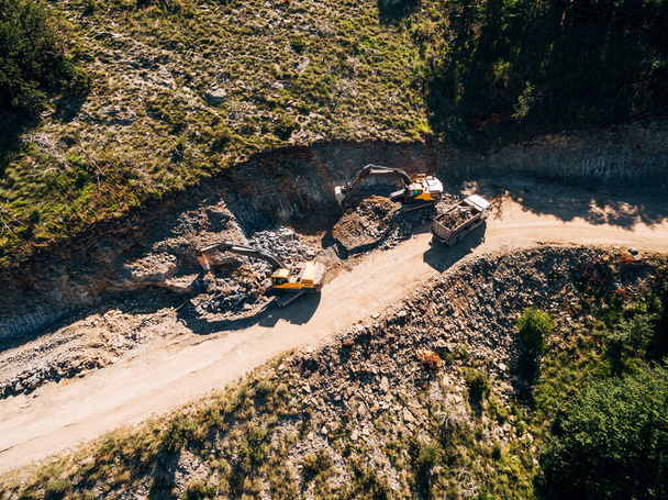 Sárga vontató megpakol egy homokkal teli kőfejtő járművet. Kilátás a drónról - Fotó, kép