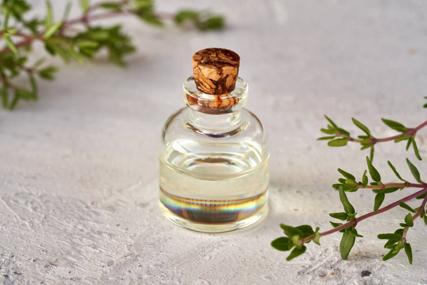 Una botella de aceite esencial con ramitas de tomillo fresco sobre fondo blanco - Foto, Imagen