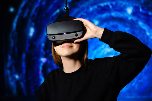 Egy lány virtuális valóság szemüvegben, játékszerekkel. Kék háttér. Kiváló minőségű fénykép - Fotó, kép