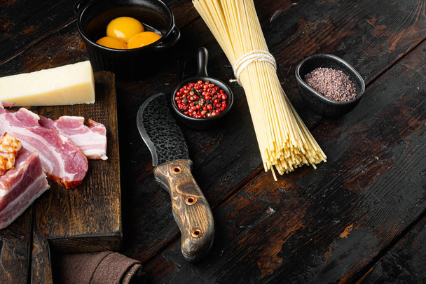 Tradycyjne włoskie makaron Carbonara Składniki. Bekon, Spaghetti, ser parmezan i pecorino, jajko, czosnek, na starym ciemnym drewnianym stole, z miejscem na tekst - Zdjęcie, obraz