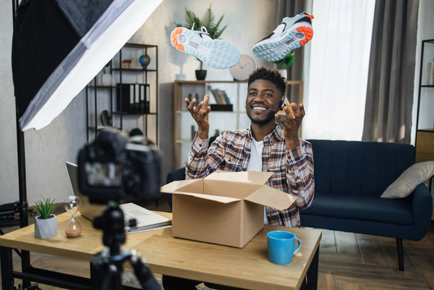 Afro man unboxing sneakers for creating video content - Foto, imagen