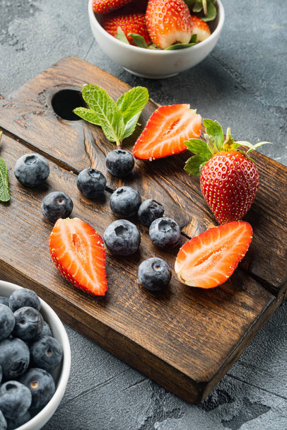 Свіжі соковиті стиглі ягоди полуниця, чорниця, на сірому фоні
 - Фото, зображення