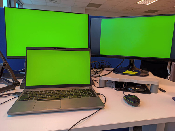 Chromagrüner Bildschirm eines Laptops auf einem Holztisch. Hintergrund verschwimmen lassen. Büroarbeitsplatzkonzept. Chromakey PC-Monitor - Foto, Bild