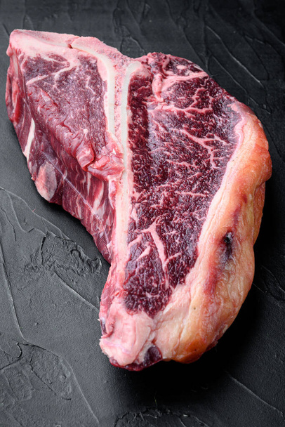 Raw fresh dry aged beef T-bone steak set, on black stone background - Фото, зображення