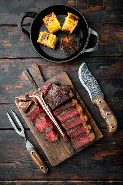 Barbecue dry aged Wagyu Porterhouse Steak sliced medium rare cooked marbled meat set, on wooden serving board, on old dark  wooden table background, top view flat lay - Foto, imagen