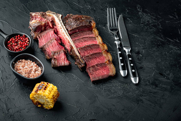 Barbecue dry aged Wagyu Porterhouse Steak sliced medium rare cooked marbled meat set, on black stone background, with copy space for text - Foto, Imagen