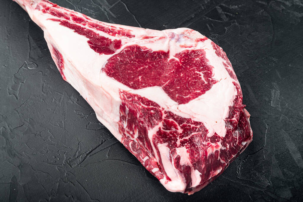 Tomahawk beef steak raw set, on black stone background, with copy space for text - Foto, Bild