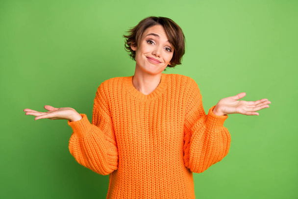 Portrait of optimistic nice brunette lady shrug shoulders wear orange sweater isolated on pastel green background - Zdjęcie, obraz