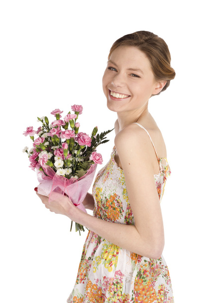 Happy attractive young woman in dress holding bouquet of carnation flowers, isolated on white background - Fotó, kép