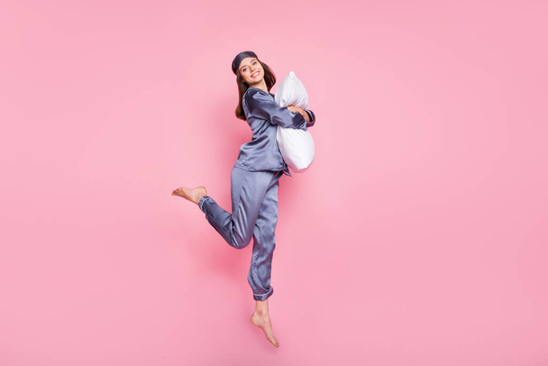 Pełna długość ciała rozmiar zdjęcie dziewczyny w piżamie przytulanie obejmujący poduszkę skoki izolowane na pastelowym różowym tle kolor - Zdjęcie, obraz