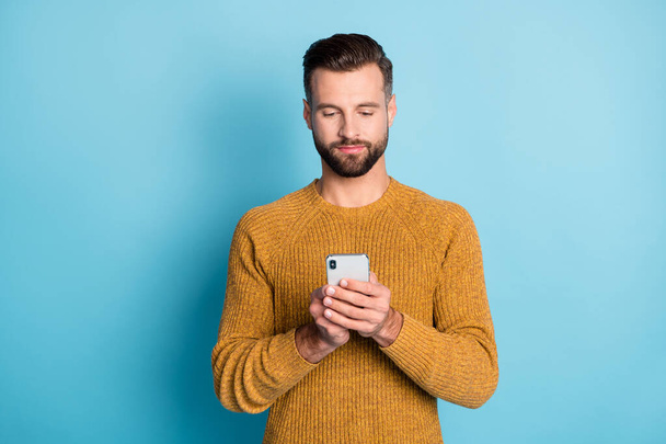 Portrait of attractive focused guy wearing casual knitted sweater using device browse web isolated over bright blue color background - Photo, Image