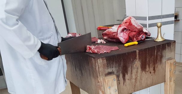 м'ясове м'ясо на дерев'яній лавці, а м'ясник ріже його в традиційному грецькому магазині
 - Фото, зображення