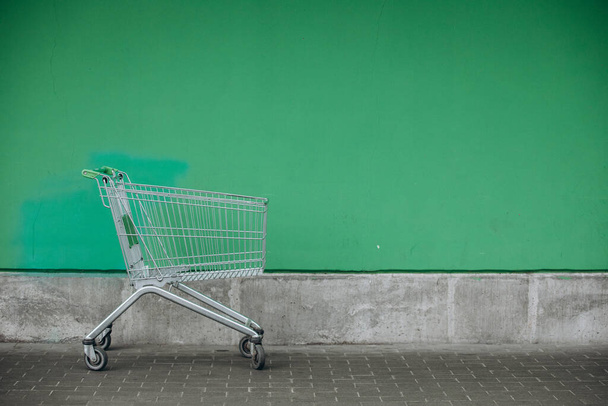 корзина супермаркета и зеленая стена - Фото, изображение
