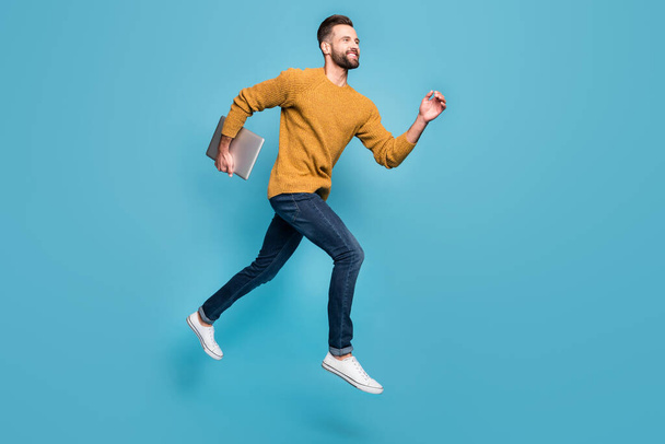 Full length body size view of nice cheerful motivated guy jumping running carrying laptop isolated on bright blue color background - Fotografie, Obrázek