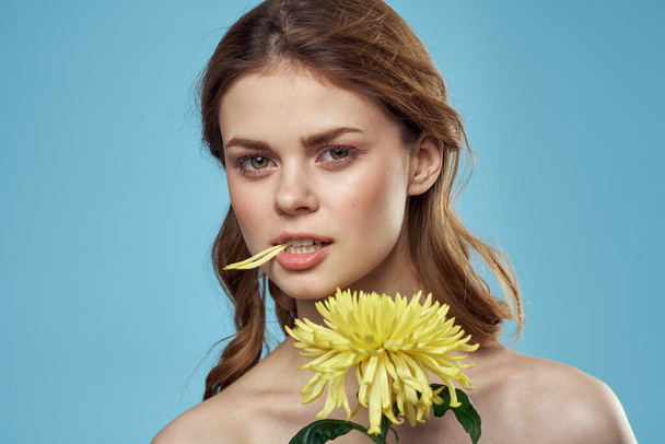 beautiful woman with yellow flower near face smiling cropped view portrait of bared shoulders - Фото, зображення