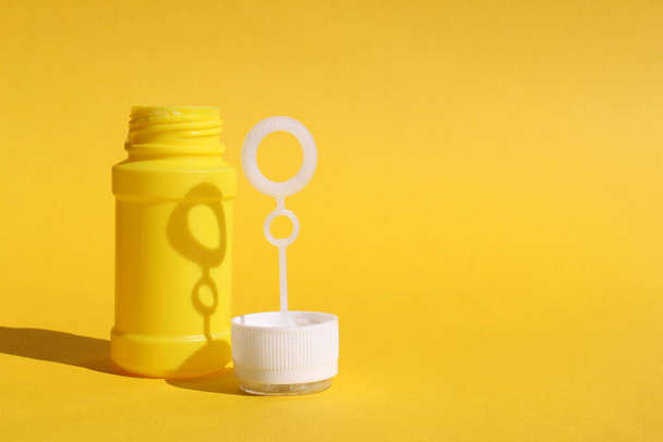 Yellow bottle for soap bubbles stands on yellow background with place for text - Foto, imagen