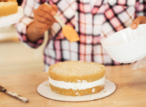 Close-up female hands smearing cake cakes with cream - Photo, image