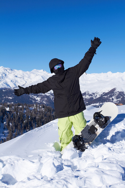 snowboarder in zwarte jas poseren in besneeuwde bergen - Foto, afbeelding