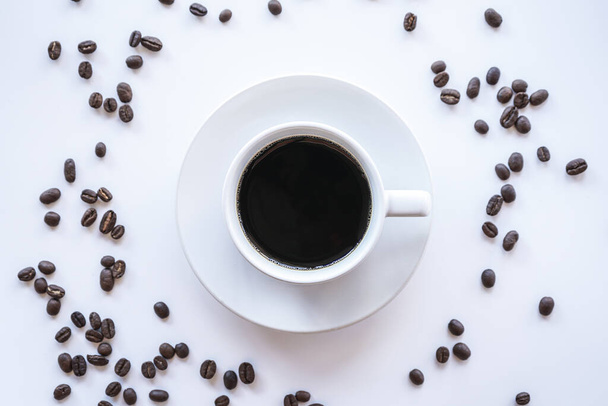 чашка кофе с жареными бобами на белом фоне - Фото, изображение