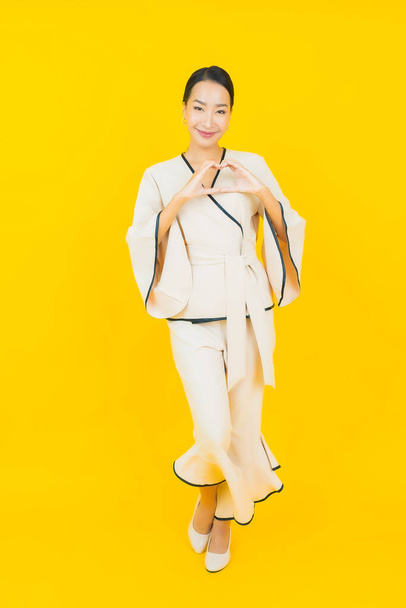 Retrato bonito jovem negócio asiático mulher com sorriso e ação amarelo fundo - Foto, Imagem