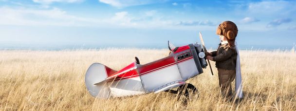 Young aviator with model airplane in the field on a sunny day - 写真・画像