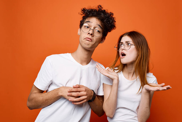весела молода пара в білих футболках емоції спілкування помаранчевий фон
 - Фото, зображення