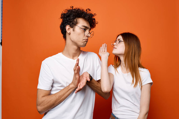 allegra giovane coppia in bianco t-shirt emozioni comunicazione arancione sfondo - Foto, immagini