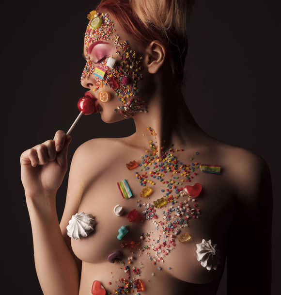 Naked woman in sweet candies licking lollipop - Foto, imagen