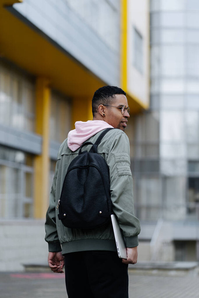 Mladý muž nosí jaket a batoh venku drží notebook - Fotografie, Obrázek