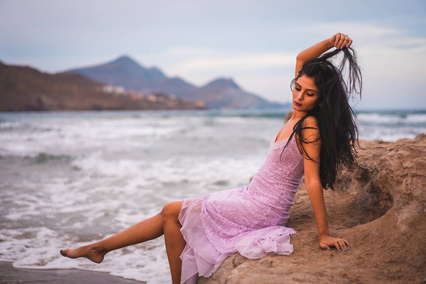 Portrait of a young brunette Caucasian woman in a pink cloth dress, on the beach by the sea in Cabo de Gata, Nijar - Fotoğraf, Görsel