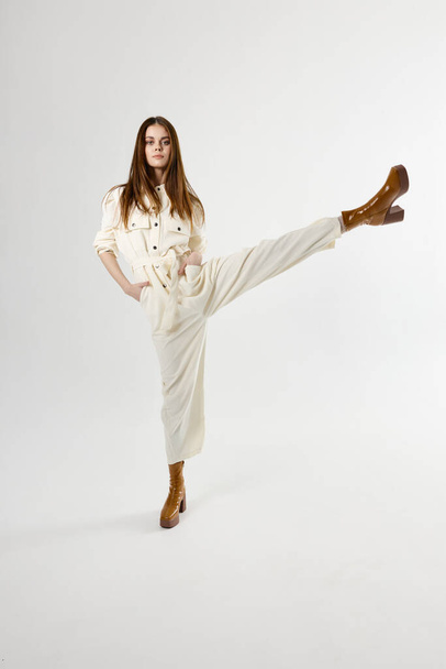 beautiful woman in white jumpsuit with raised leg up on isolated background - Zdjęcie, obraz