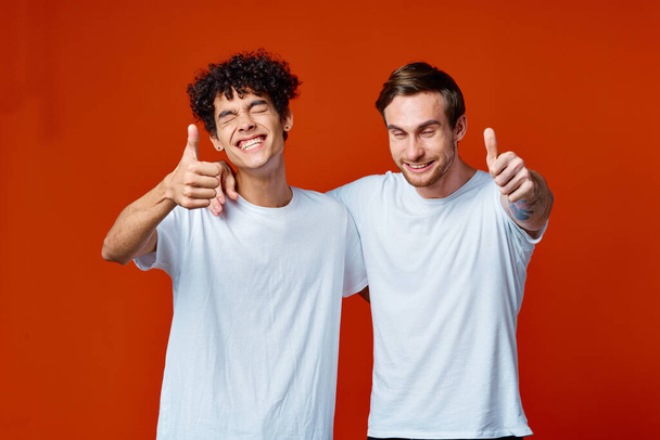 Kaksi miestä valkoisissa t-paidoissa hauskoja tunteita käsi eleitä ystävyys halauksia - Valokuva, kuva