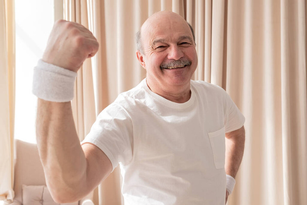 Hombre mayor mostrando músculo siendo orgulloso con su salud - Foto, imagen