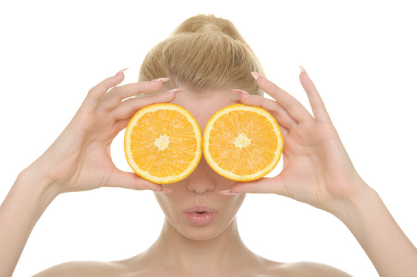 Young woman holds halves of oranges before eyes isolated in white - Foto, immagini