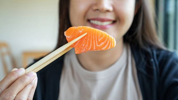 Woman eating a sashimi salmon. - Фото, зображення