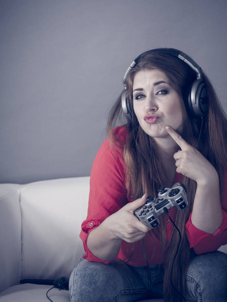 Nerd geek young adult women playing on the video console holding game pad sitting on sofa. Gaming gamers concept. - Photo, Image