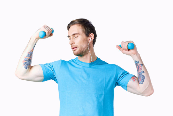 człowiek robi ćwiczenia dla mięśni ramion z hantlami na lekkim tle - Zdjęcie, obraz