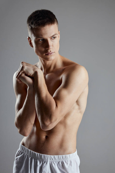 guy with athletic physique joined hands near shoulder on gray background cropped view - Photo, Image