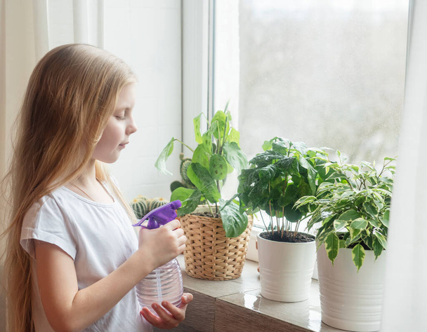 Little girl splashing water on house plants. Home gardening - Valokuva, kuva