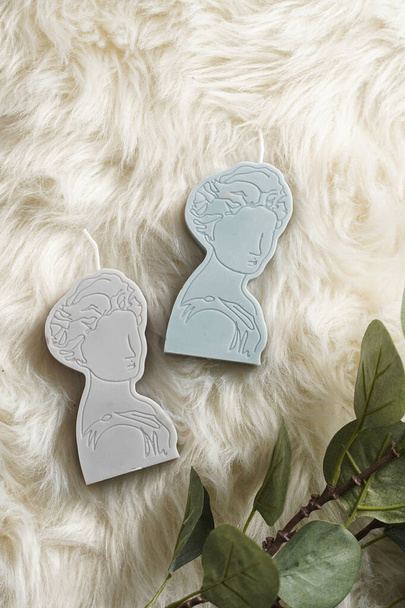 Two grey and blue candles shaped as greek goddess on a white faux fur surface - Photo, Image