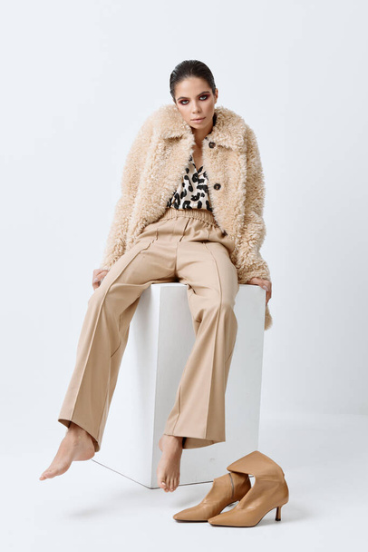atraente mulher elegante vestindo roupas bege descalço posando sentado - Foto, Imagem